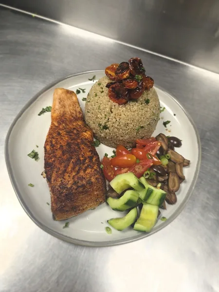 Salmon over quinoa with roasted tomatoes, cucumber and mushrooms, plated