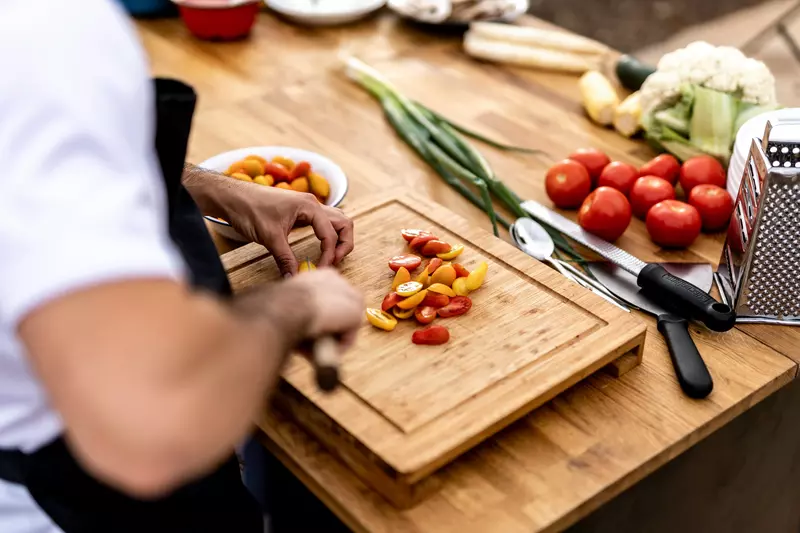 Chef slicing tomatoes on a wooden board